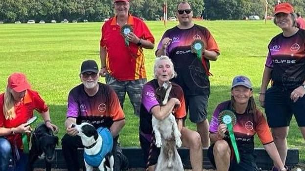 A photograph of members of Eclipse Flyball Club with their dogs who are all part of the Eclipse team