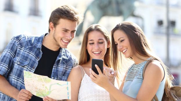 Group of 3 young people with map and cell