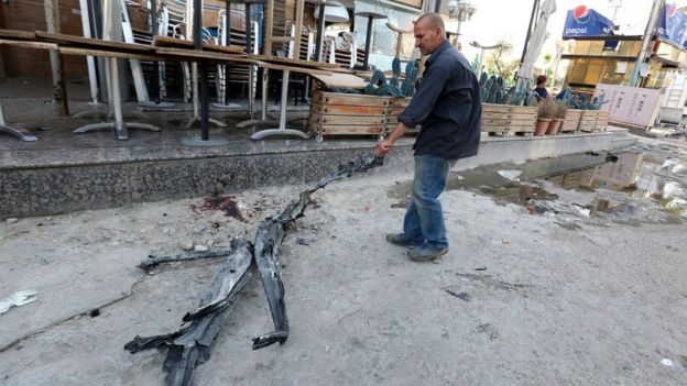 An Iraqi civilian drags a piece of debris at the site of bombing at Al-Faqma ice cream shop in Karrada, Baghdad (30 May 2017)