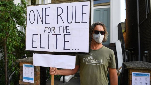 A protester holds a placard saying "One rule for the elite" outside Cummings' home in London on 25 May 2020