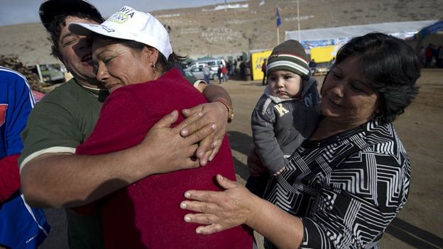 Familiares de los mineros se abrazan tras conocer que los 33 estaban bien y en buen estado de salud.