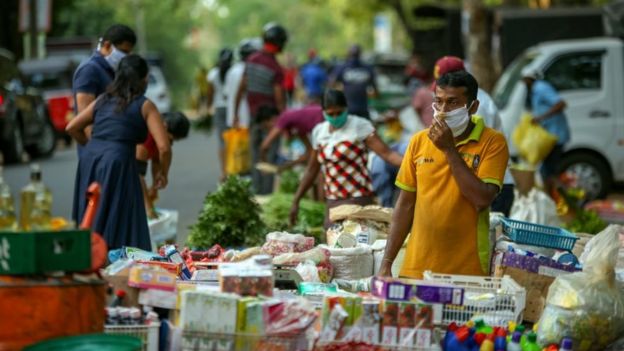 A Sri Lankan vegetable vendor wearing a protective face awaits for customers at a local vegetable market after the curfew was lifted for few hours at Anuradhapura, Sri Lanka, on March 26, 2020. According to the data from the Sri Lanka's Epidemiology Unit at the Health Ministry, 255 persons are currently in hospitals with the symptoms of COVID-19 virus while confirmed cases are 102. Curfew is imposed in Colombo, Gampaha and Kaluthara districts after being identified as high risk zones for Covid-19 outbreak in Sri Lanka.
