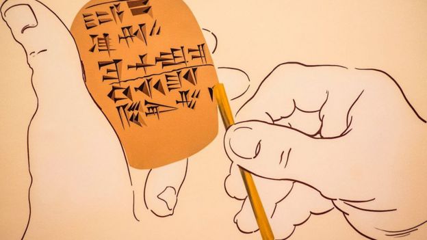 Dibujo que muestra manos sosteniendo tableta de arcilla e imprimiendo símbolos