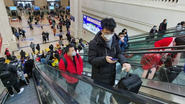 Des personnes masquées montent dans les escaliers roulants de la gare de Hankou le 22 janvier 2020 à Wuhan