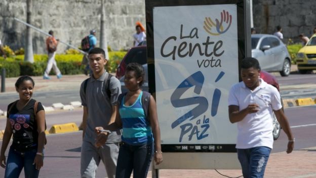 Colombianos pasan junto a un cartel del Sí al plebiscito nacional