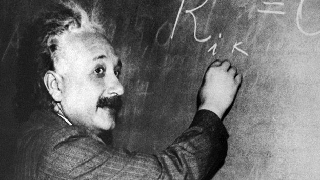 Albert Einstein writing an equation on a blackboard