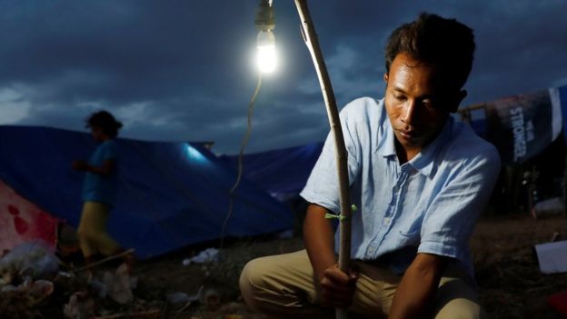 Seorang warga di Senggigi, <a href='https://medan.tribunnews.com/tag/lombok' title='Lombok'>Lombok</a>, yang khawatir akan gempa susulan memasang lampu di depan tenda tempat mereka berlindung.