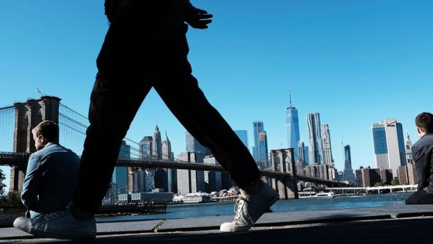 People relax along a promenade in Brooklyn on an unseasonably warm day on October 20, 2017 in New York City. Temperatures across New England are expected to remain warm with abundant sunshine through the weekend