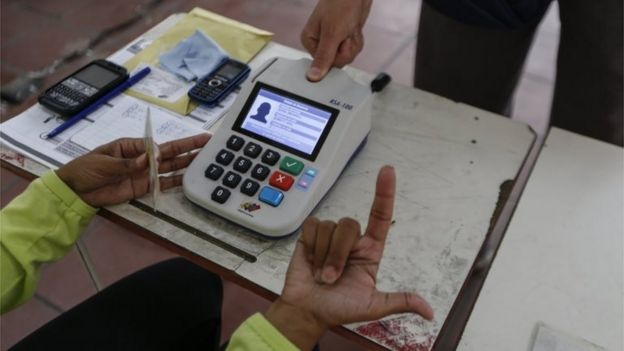 A polling official checks identification as Venezuelans vote in the elections of the National Constituent Assembly, in Caracas, Venezuela, 30 July 2017.