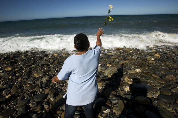 Una mujer lanza flores al mar el 16 de diciembre de 2009 para conmemorar el décimo aniversario del deslave de Vargas, ocurrido en Venezuela 1999.