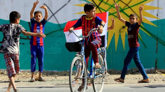 A boy drives a bicycle with an Iraqi flag in Dibis area on the outskirts of Kirkuk