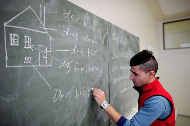 Un joven escribe alemán en una pizarra.