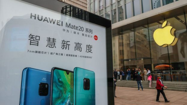 A Huawei poster is displayed outside an Apple store in Shanghai on October 26, 2018.