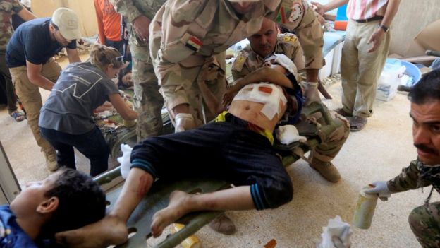 Iraqi security forces carry wounded Iraqi boys from clashes in western Mosul, Iraq (3 June 2017)