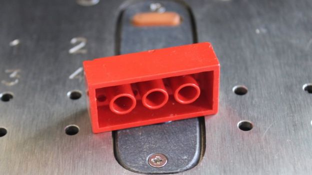 Picture of red Lego brick on machine