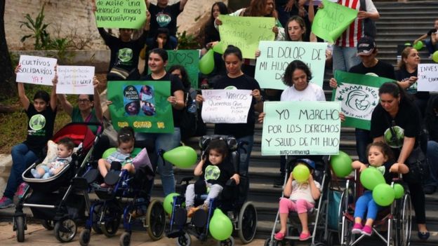 Mulheres da organização 'Mamãe Cultiva', acompanhadas de seus filhos pequenos (alguns em cadeira de rodas), protestam com cartazes pela legalização do uso medicinal da maconha no Paraguai