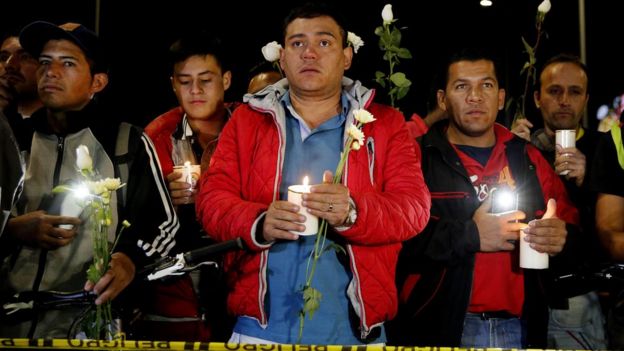 Citizens and police hold candles during a vigil at the Francisco de Paula Santander General Police Cadet School in Bogota