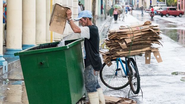 Hombre sacando cartones de la basura