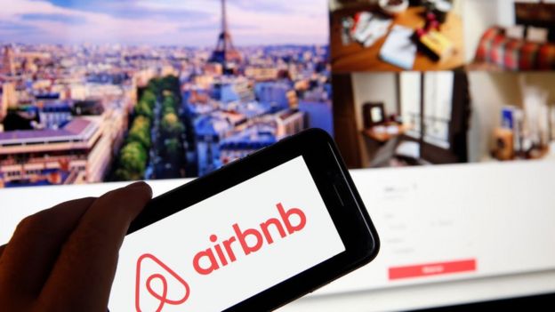 Logo de Airbnb con la página web de fondo.