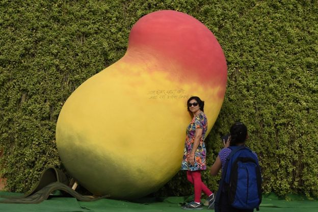 Mujer posando junto a un mango artificial gigante