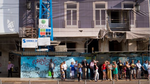 Pessoas em pé de frente a um edifício em reforma no centro de Lisboa