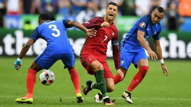 Cristiano Ronaldo (C) of Portugal is challenged by Patrice Evra (L) and Dimitri Payet (R) of France during the UEFA Euro 2016 Final