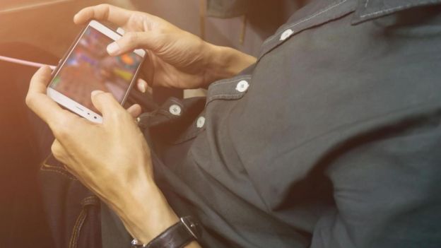 Un hombre jugando con su teléfono celular