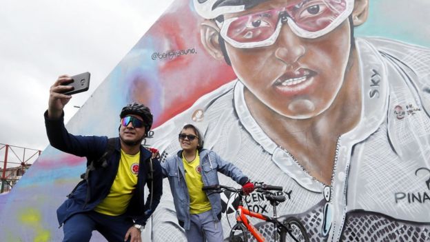 Dos aficionados se fotografía frente a un mural con el rostro de Egan Bernal en Zipaquirá.