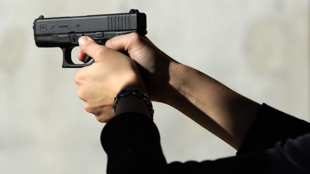 A woman's hands rest on the trigger of a Glock 27 .40 caliber handgun