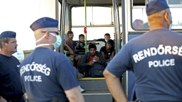 Hungarian police officers stand outside a bus with migrants at a migrant collection point in Roszke, Hungary - 12 September 2015