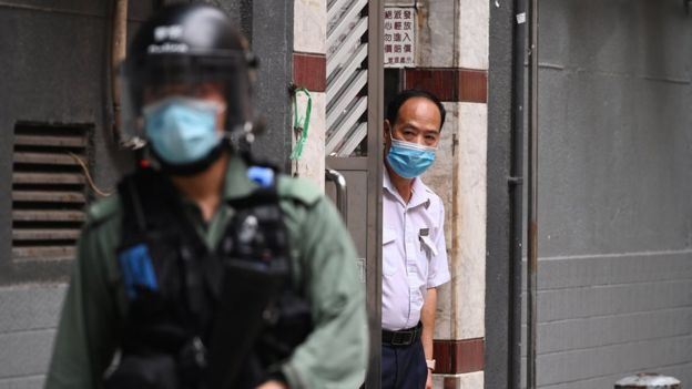 Ένας άντρας κοιτάζει έξω από μια πόρτα καθώς μια αστυνομία ταραχών περνά από μια διαδήλωση ενάντια σε έναν νέο νόμο περί εθνικής ασφάλειας κατά την 23η επέτειο από την ίδρυση της Ειδικής Διοικητικής Περιφέρειας του Χονγκ Κονγκ στο Χονγκ Κονγκ της Κίνας