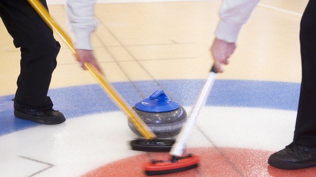 Sweepers guide a curling stone into the 'house'