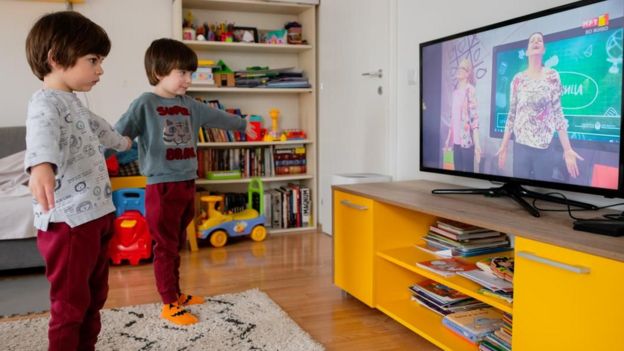 Meninos se exercitando diante de tela