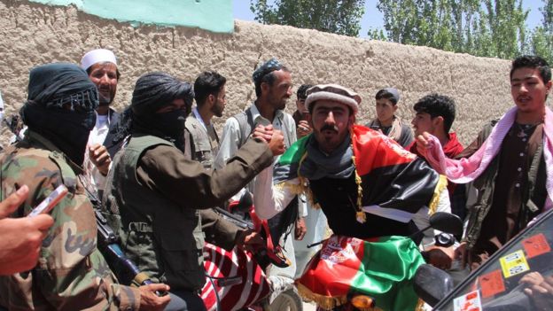 مسلح من طالبان يحمل العلم الأفغاني