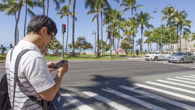hombre usando celular en las calles de Hawái.