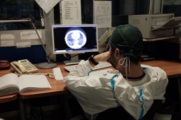 A nurse stares at a screen at a desk