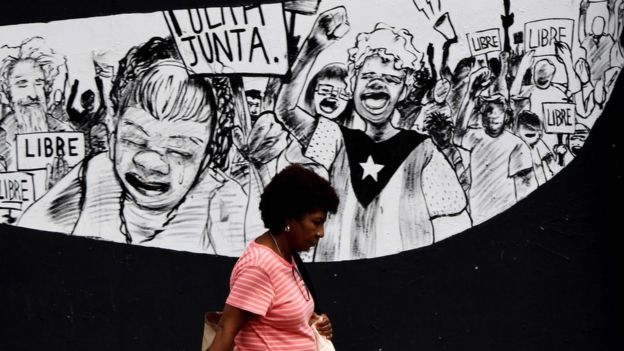 Un mural en Puerto Rico con personas sosteniendo carteles que dicen: