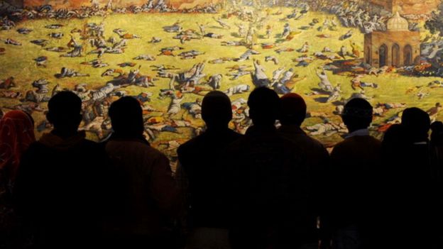 Indian visitors look at a painting depicting the Amritsar Massacre at Jallianwala Bagh in Amritsar