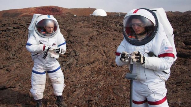 Dos personas vestidas de astronautas en un campo de entrenamiento