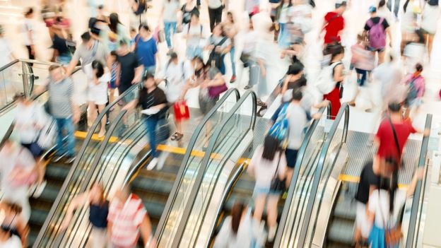 Pessoas subindo e descendo escada-rolante de shoppping