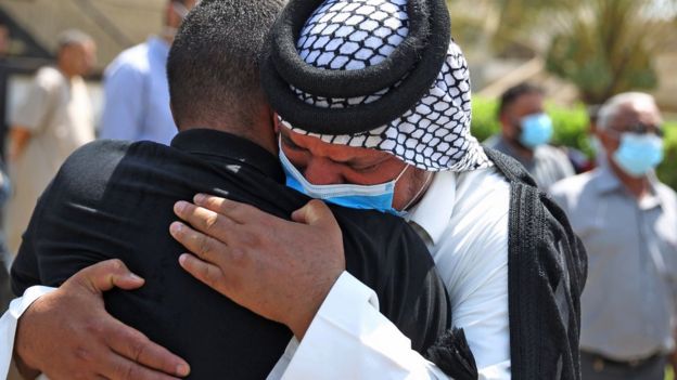 Mourners hug each other at the funeral of Hisham al-Hashimi in Baghdad (7 July 2020)