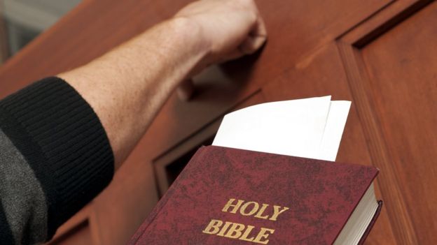 Foto de banco de imagens com pessoa batendo na porta com bíblia na mão