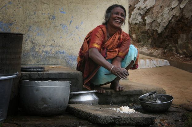 Una mujer lavando platos en India.