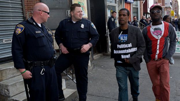 Dos estadounidenses negros caminan frente a dos policías blancos.