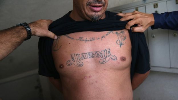 Agentes del ICE inspeccionan los tatuajes de un hombre detenido en Los Ángeles, California