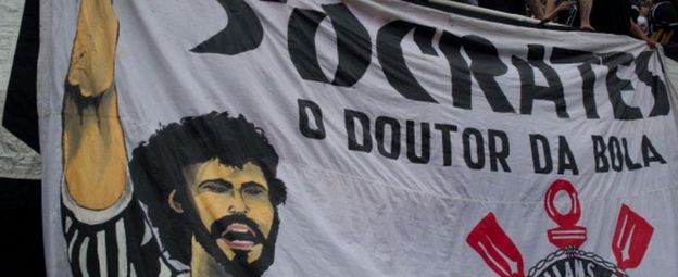 Supporters of Corinthians stand next to a banner in homage of the late footballer Socrates, during the Brazilian Championship final date match against Palmeiras, at the Pacaembu stadium on 4 December 2011 in Sao Paulo, Brazil