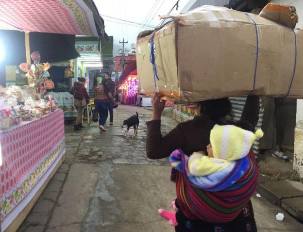 Mujer carga a su hijo en un mercado.