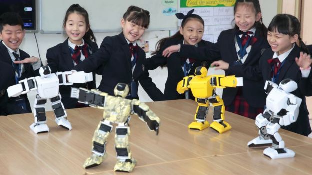 Çinli ilkokul öğrencileri ve minyatür robotlar.
