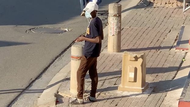 Man waits on a street corner to sell cigarettes