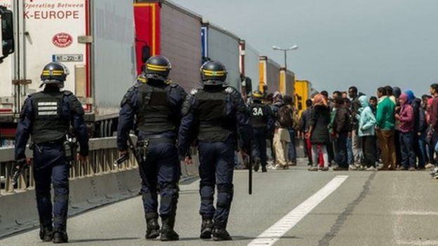 French riot police approach a crowd of migrants